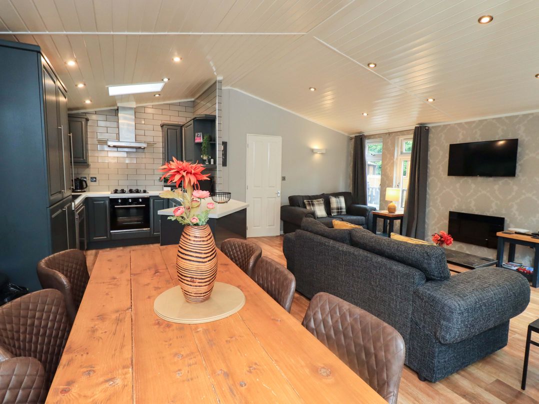 A living room with a dining table and kitchen appliances at Rydal Lodge Grasmere 24, White Cross Bay near Windermere