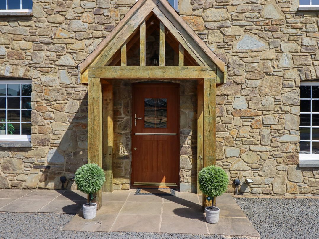 An entrance with a wooden door and stone walls at Bodaioch Cottage Trefeglwys near Caersws