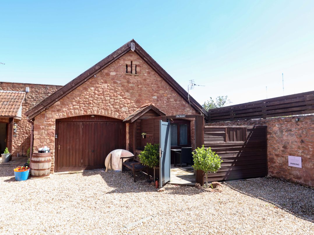 An outdoor view of a cottage entrance with garden features at The Retreat Washford near Williton