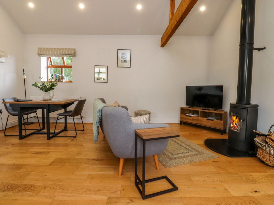 A living room with a sofa, table, and fireplace at The Stables Hall Green near Walmer Bridge