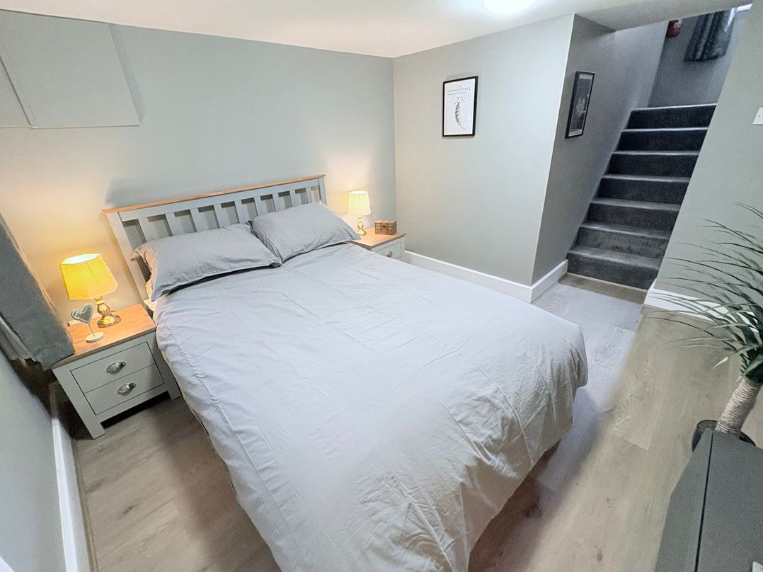 A bedroom with a bed and nightstand at The Oaks Cottage in Penrith