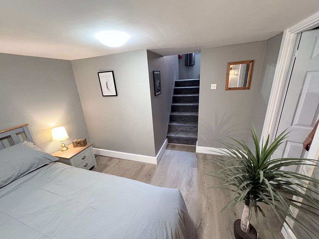 A bedroom with a bed and stairs at The Oaks Cottage in Penrith