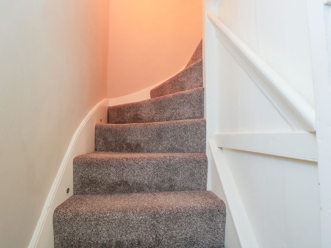 A carpeted staircase with a white handrail and wall at Millbank Cottage in Mickleton