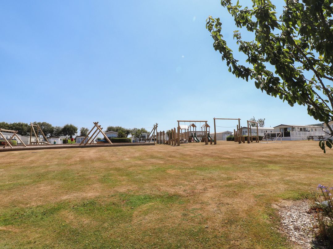 An outdoor playground with swings and climbing frame at 97 Crugan Llanbedrog