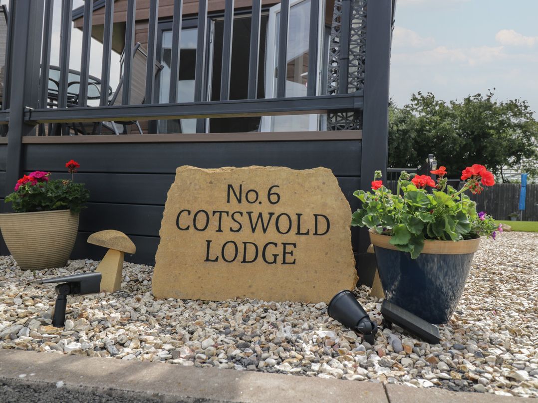 A sign stating No.6 Cotswold Lodge with flower pots in an outdoor area at The Cotswold Holiday Lodge Evesham