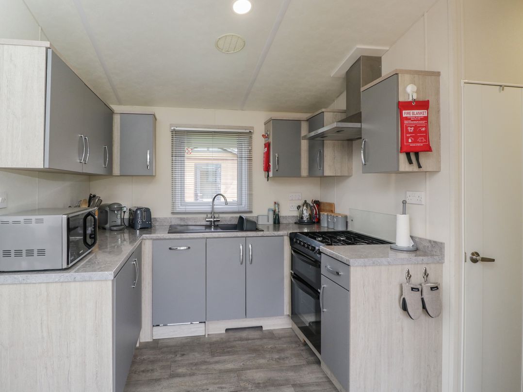A kitchen with cabinets, sink, and appliances at The Cotswold Holiday Lodge in Evesham