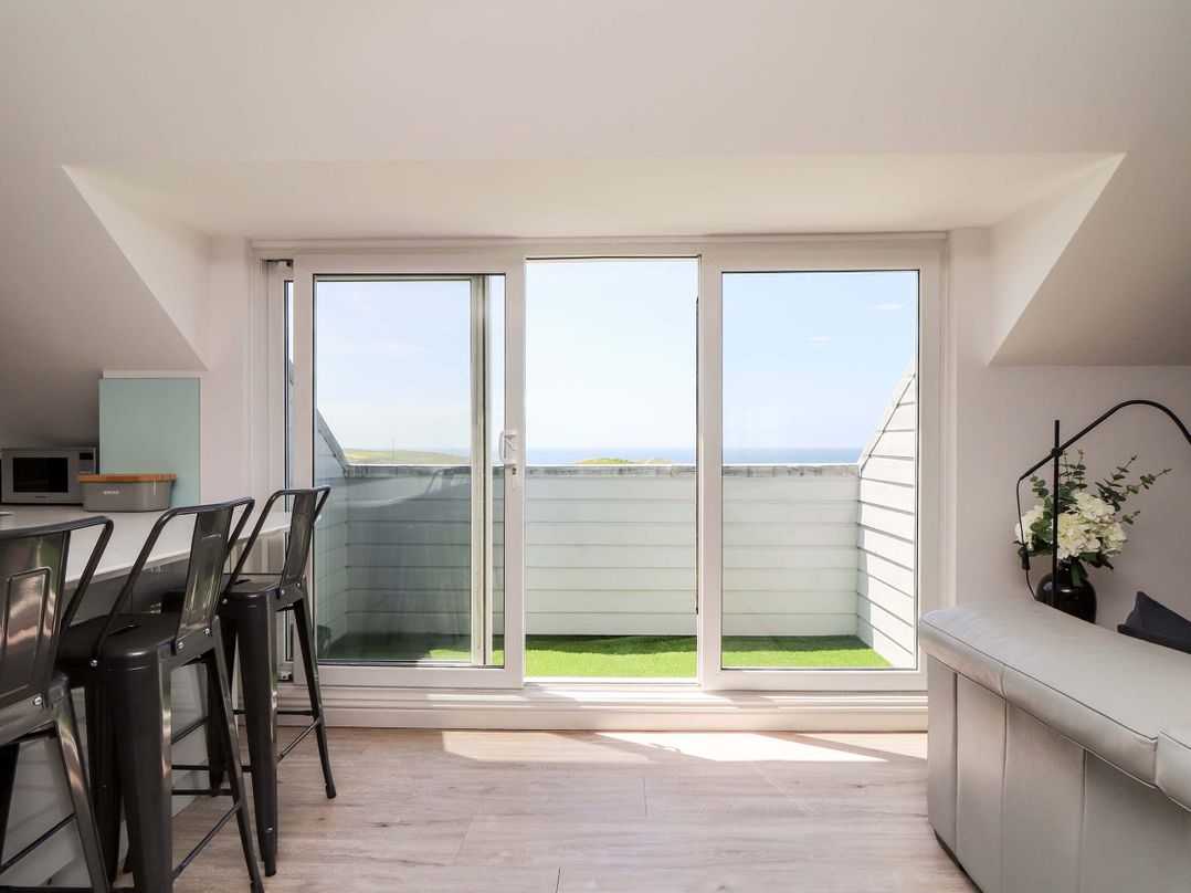 A living room with a balcony and chairs at Penthouse 23 in Newquay