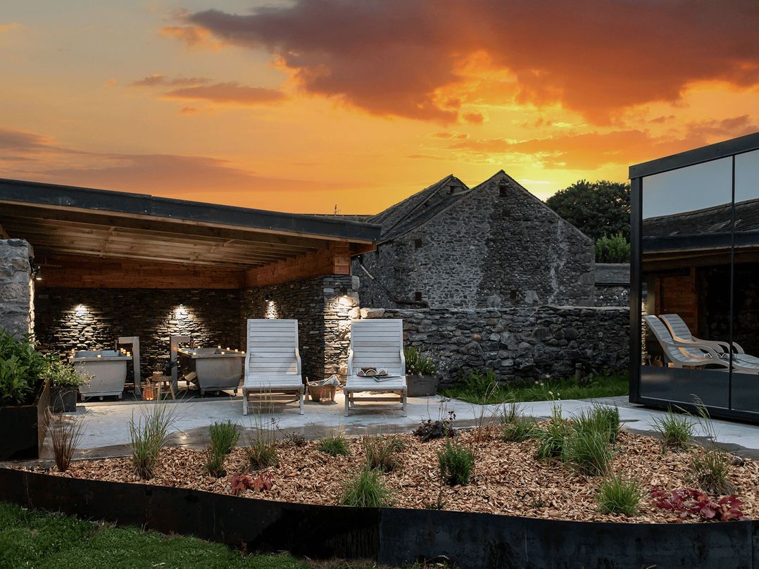 An outdoor garden with deck chairs and a stone wall at Little Heaning in Cartmel