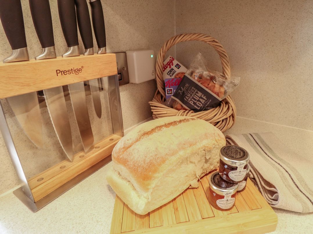 A kitchen with a bread loaf, knife block, and jam jars at Hangmans cottage in Horncastle