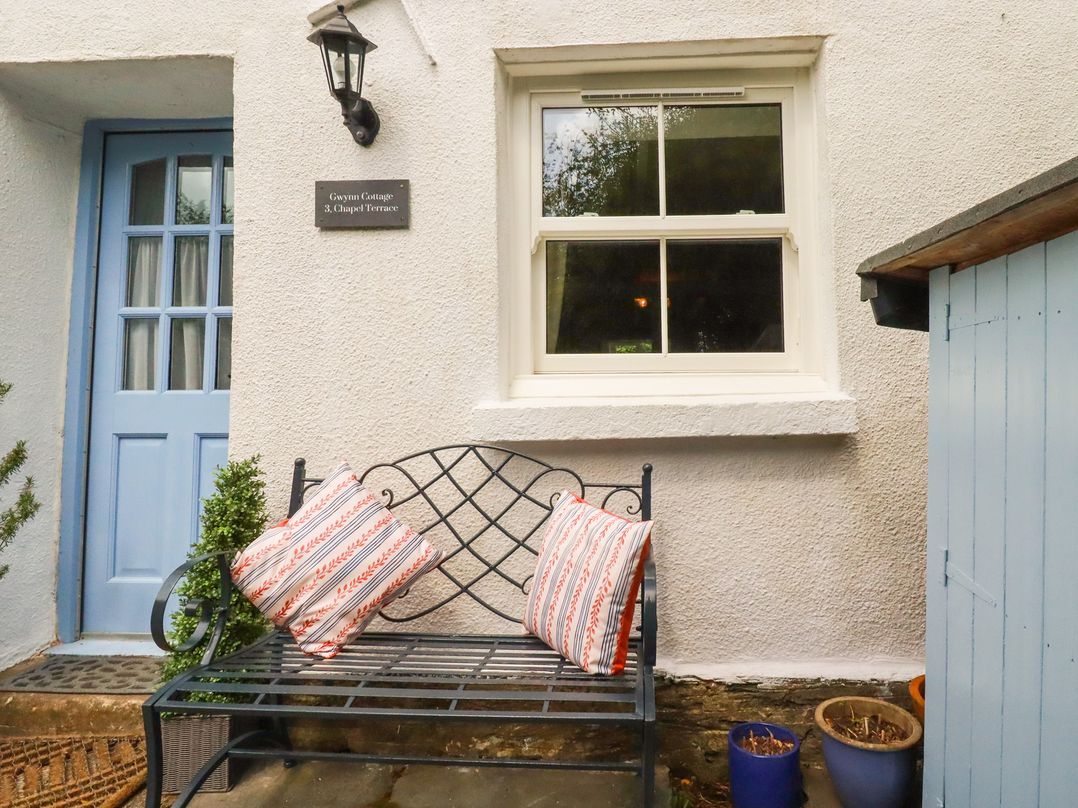 An outdoor seating area with a bench and cushions at Gwynn Cottage St Mabyn