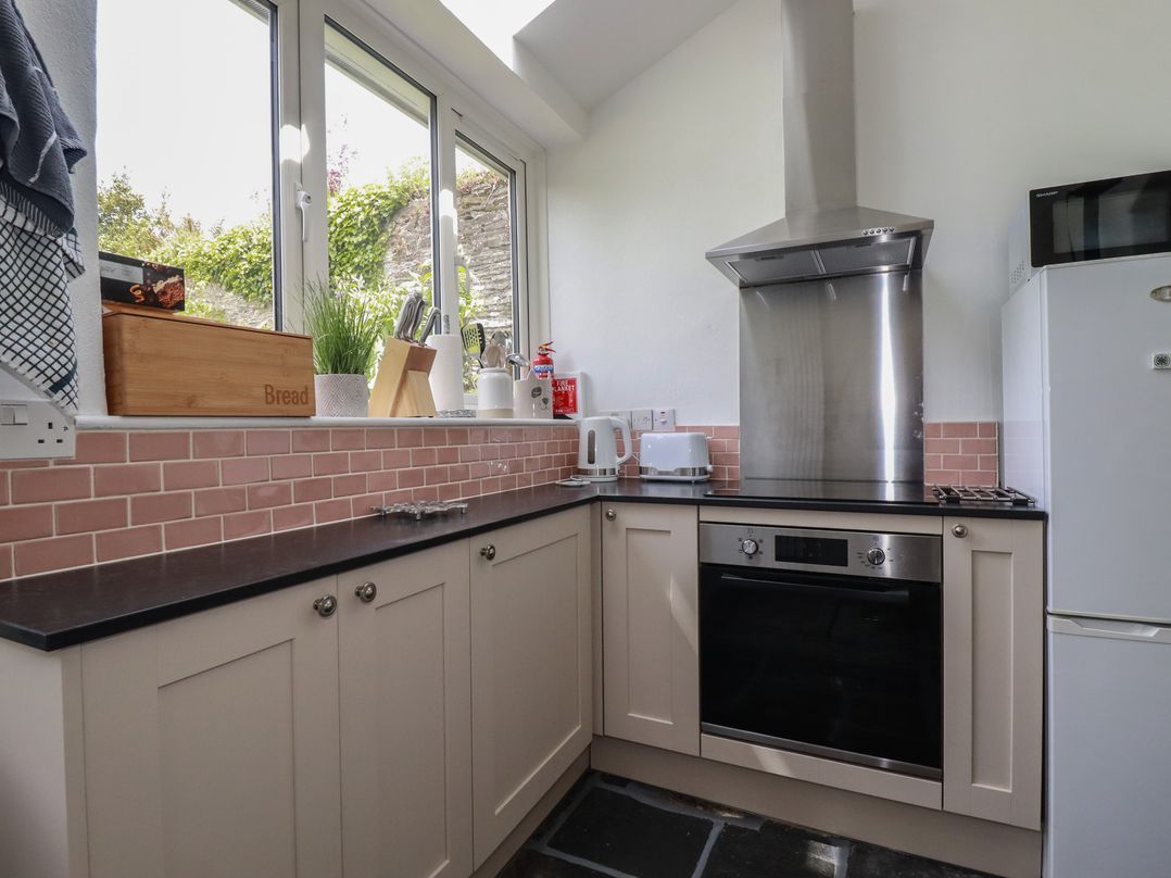 A kitchen with modern appliances and a window at Gwynn Cottage in St Mabyn