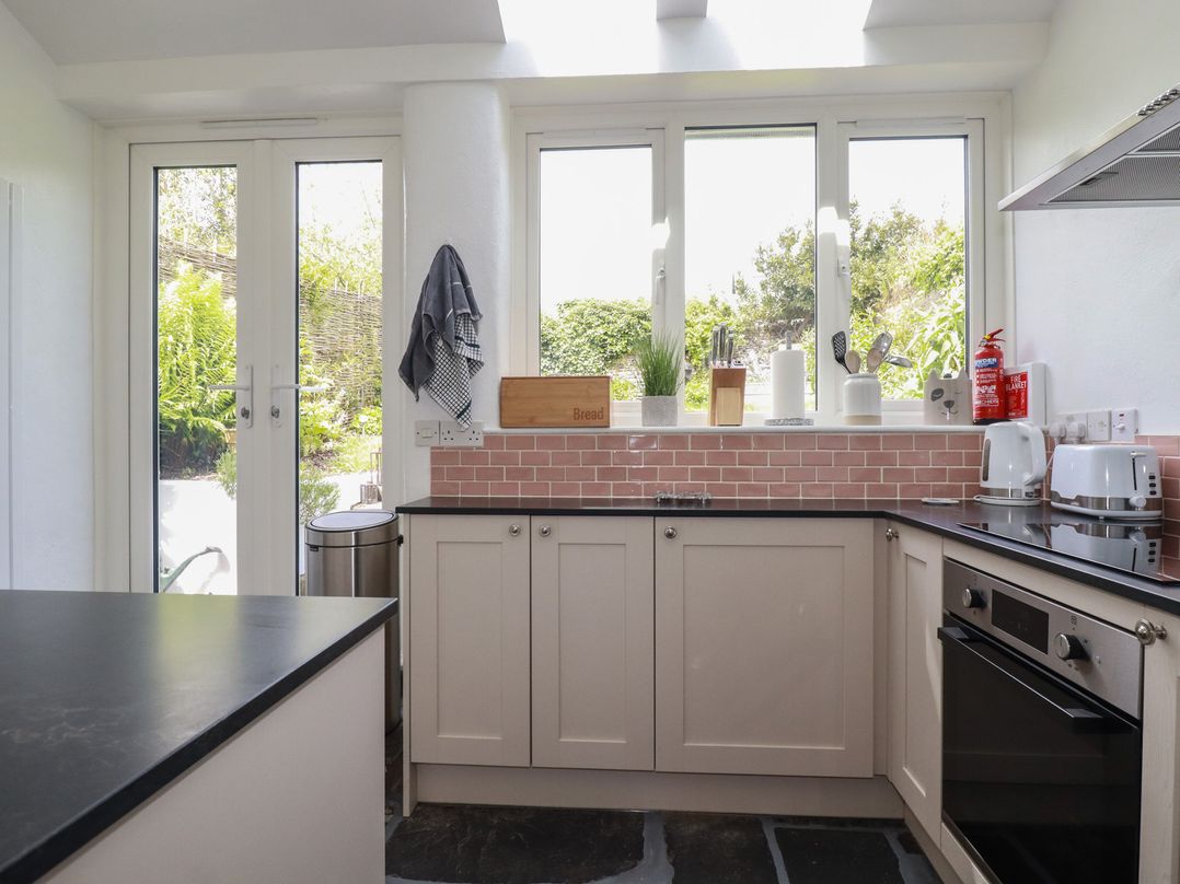 A kitchen with cabinets and appliances at Gwynn Cottage in St Mabyn