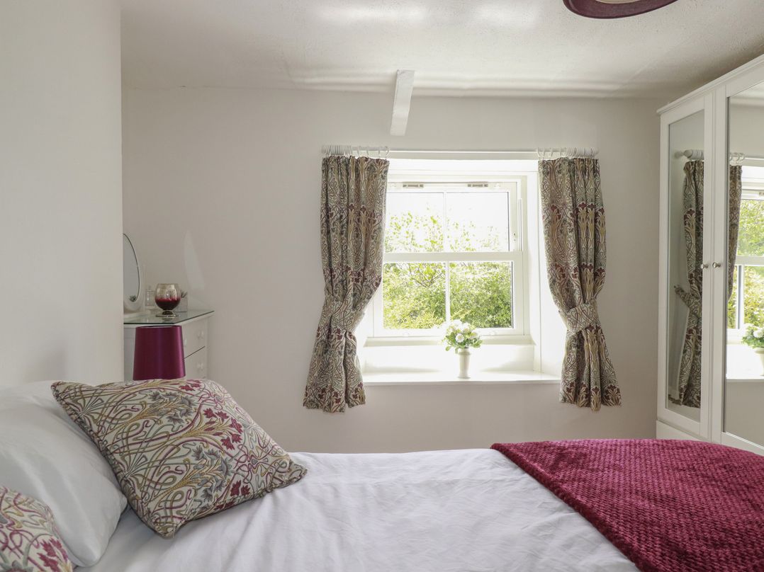 A bedroom with a bed and curtains at Gwynn Cottage St Mabyn