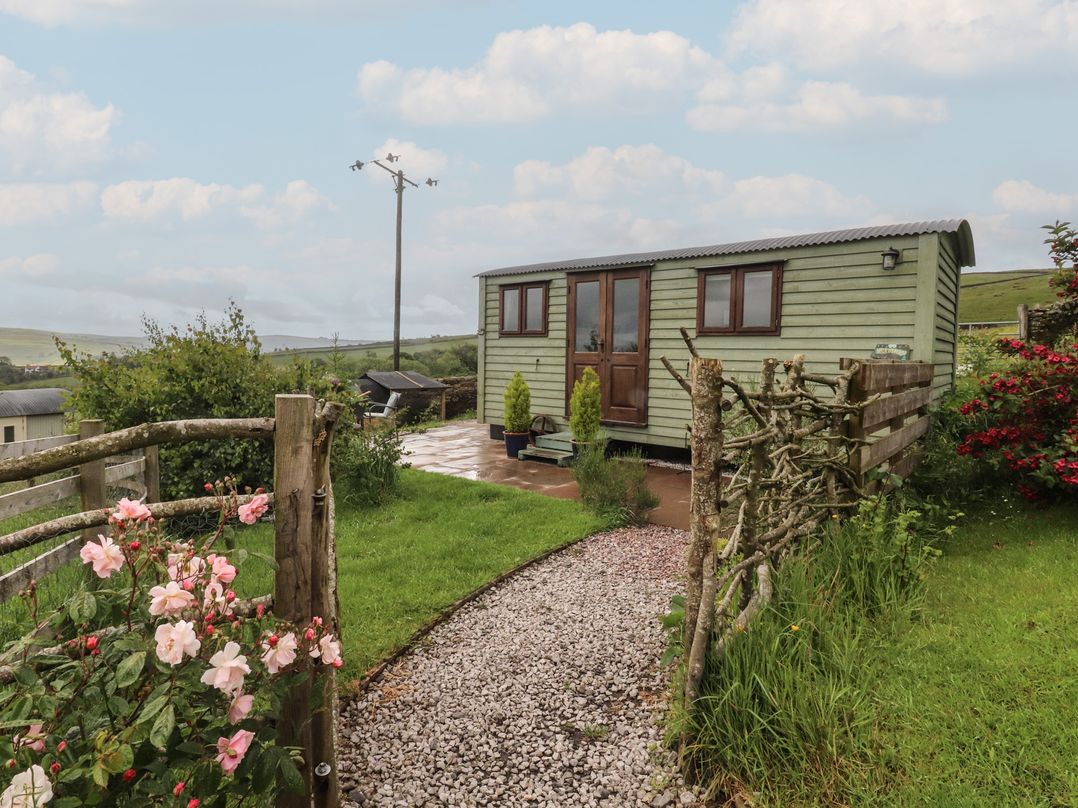 A garden with a shepherd's hut and flowers at The Herdsman Luxury Shepherds Hut Barnoldswick