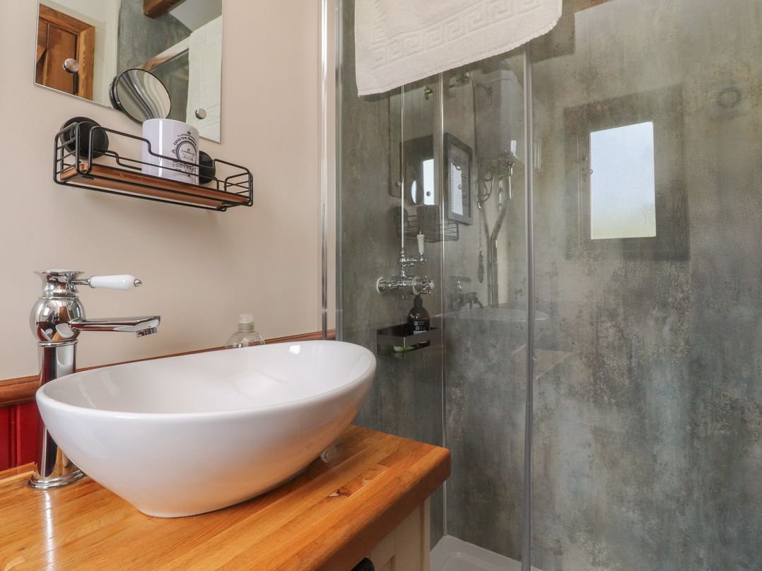 A bathroom with a wash basin and shower at The Herdsman Luxury Shepherds Hut in Barnoldswick