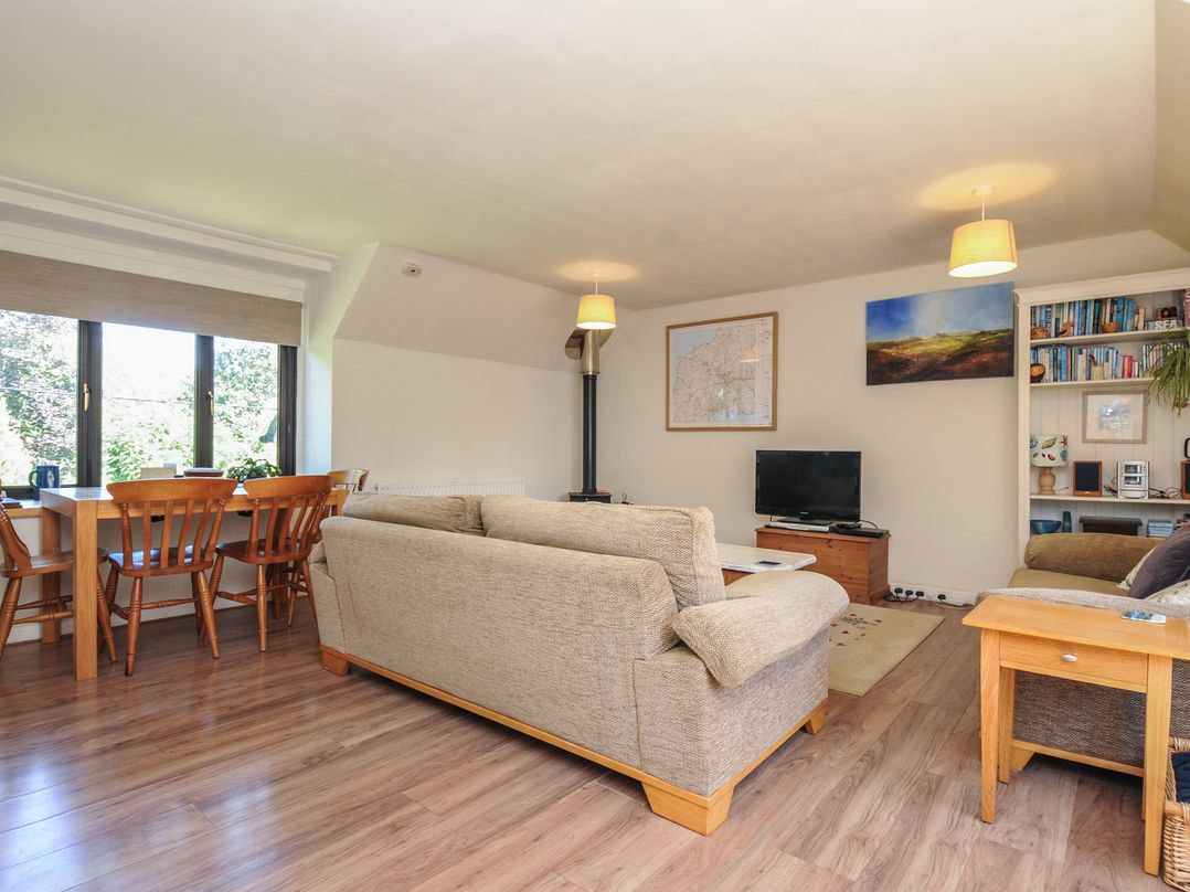 A living room with a sofa and dining area at The Mews in Blisland