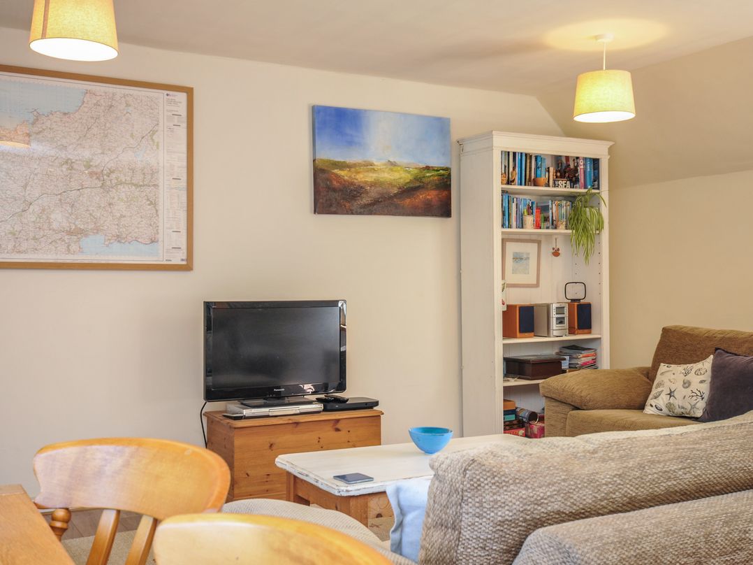 A living room with a television and books on a shelf at The Mews in Blisland