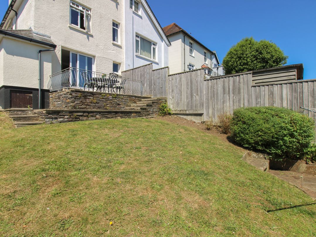 A garden with grass and patio seating at Waders Salcombe