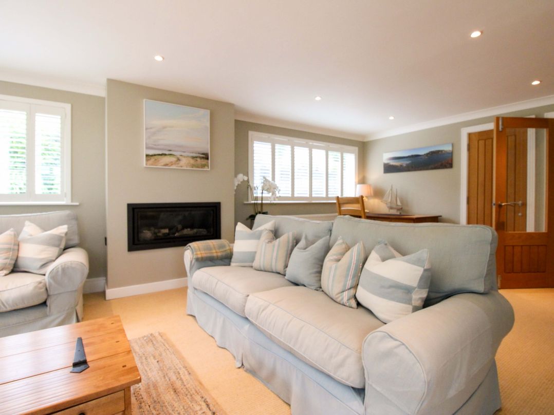 A living room with a sofa, armchair, coffee table, and fireplace at Welsummer in Salcombe
