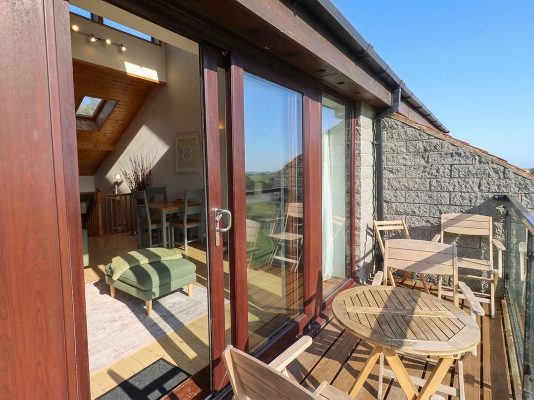A balcony with a wooden table and chairs at Links View in Embleton