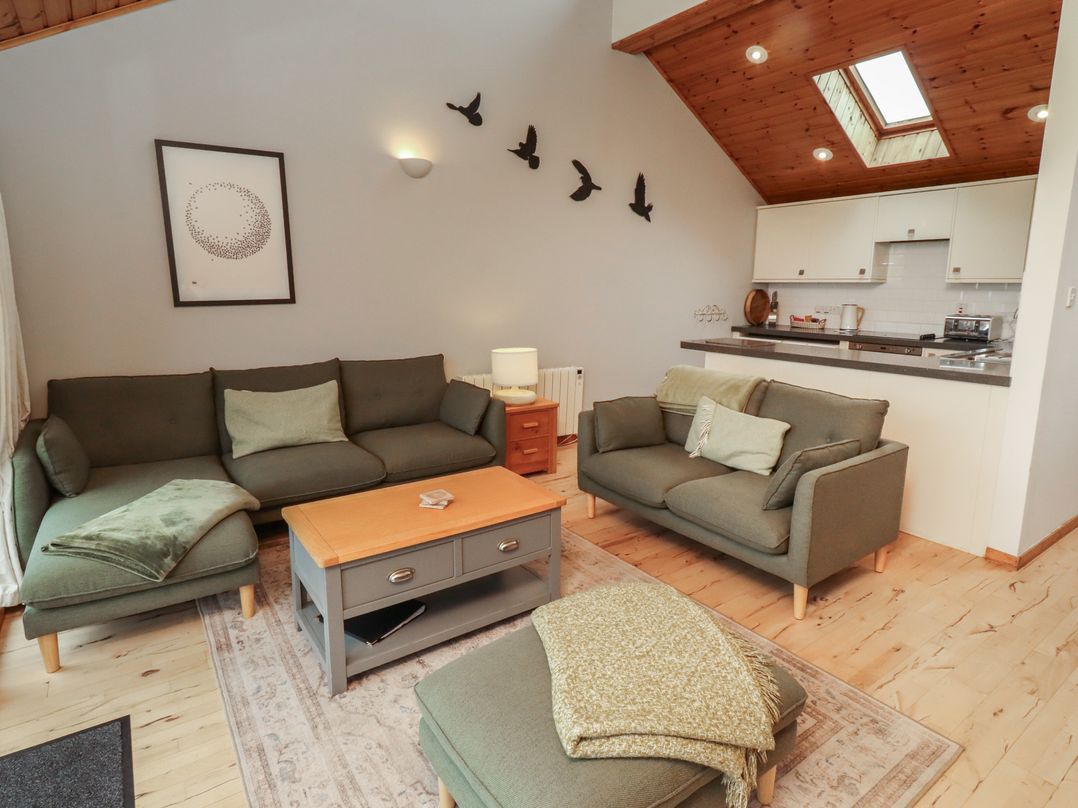 A living room with seating and kitchen counter at Links View in Embleton