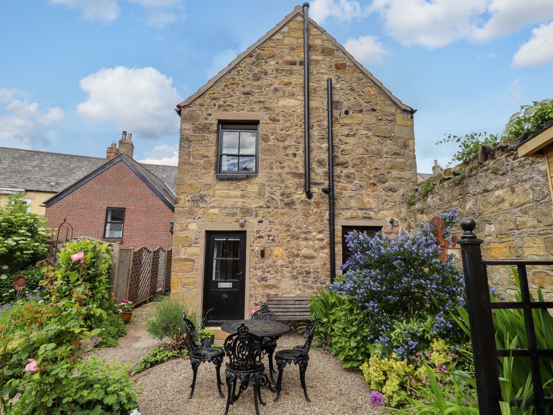 A stone building with a garden and seating area at Lavender Cottage (Bailiffgate) Alnwick