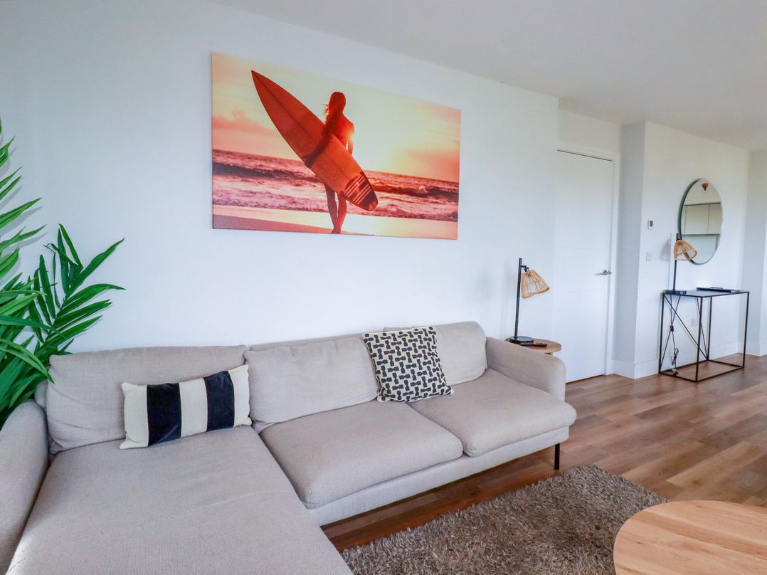 A living room with a sofa and wall art at Lavender House in Crantock