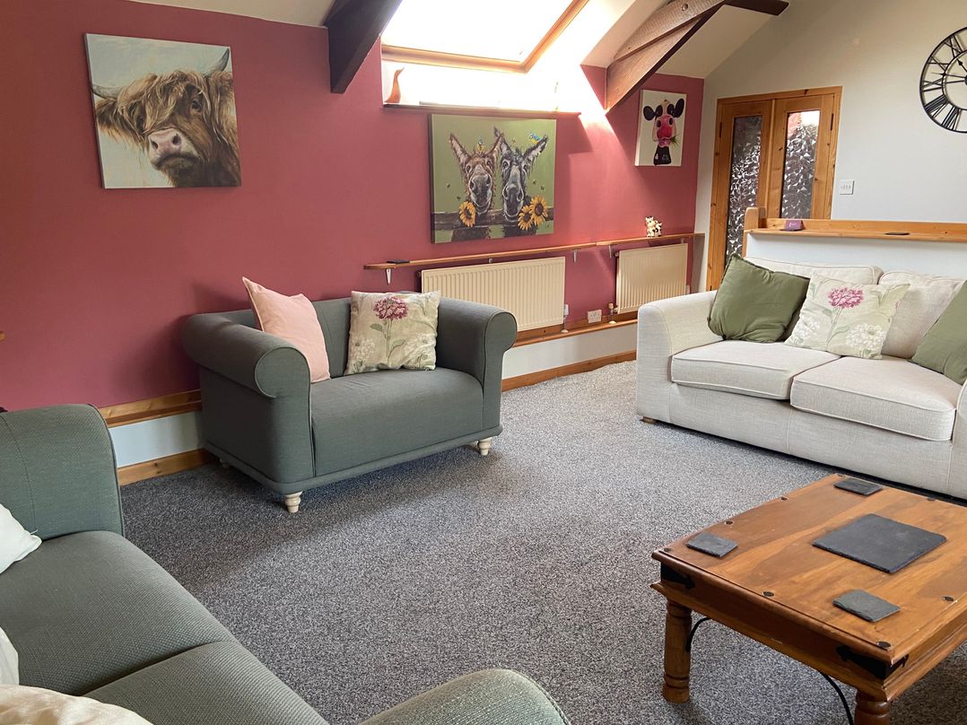A living room with sofas and wall art at Foxglove Barn in South Brent