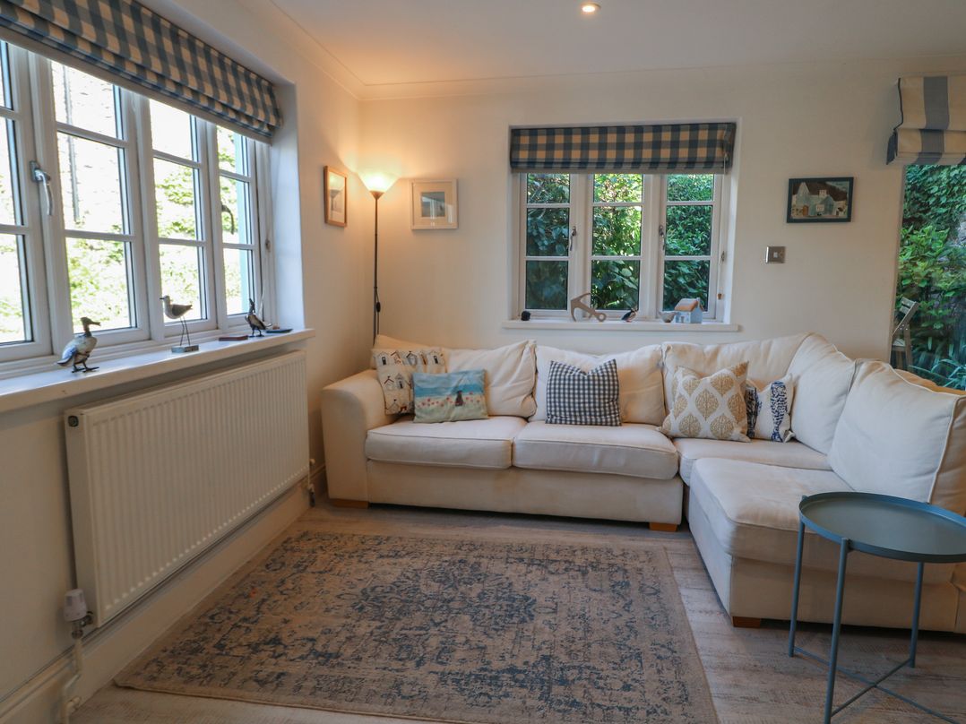 A living room with a white sofa and windows at November Cottage in Dittisham