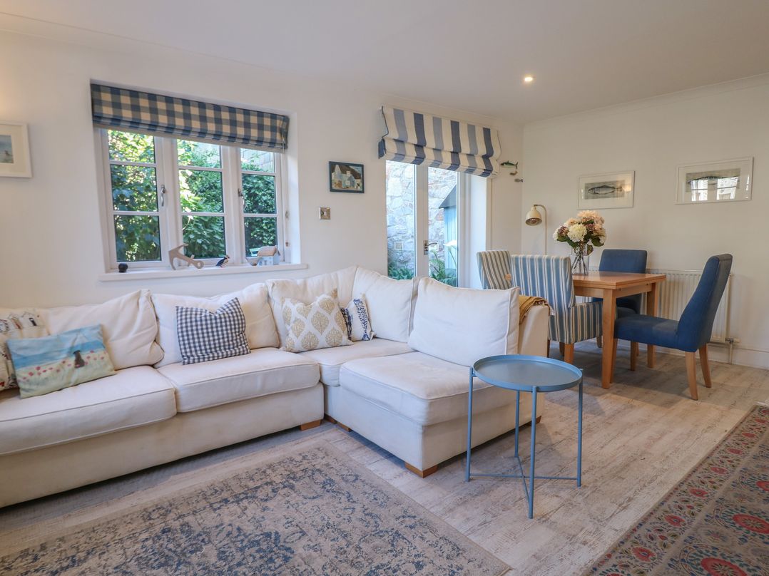 A living room with a sofa and dining table at November Cottage in Dittisham