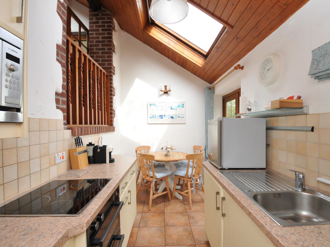 A kitchen with appliances and dining area at Shipload Cottage Hartland