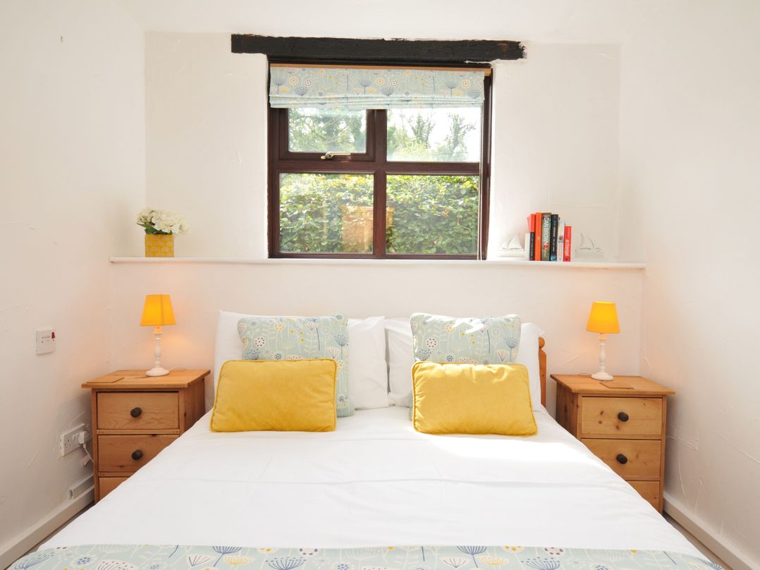 A bedroom with a bed and nightstand at Shipload Cottage in Hartland