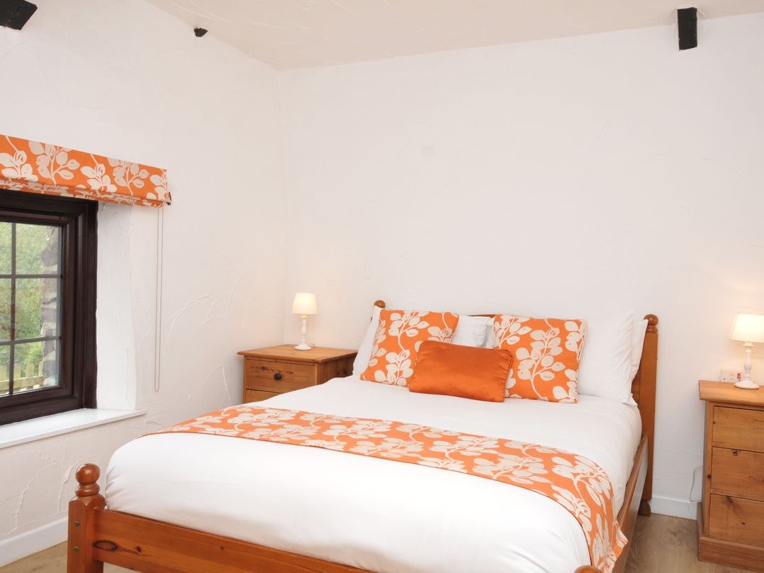 A bedroom with a bed and nightstands at Windbury Cottage in Hartland