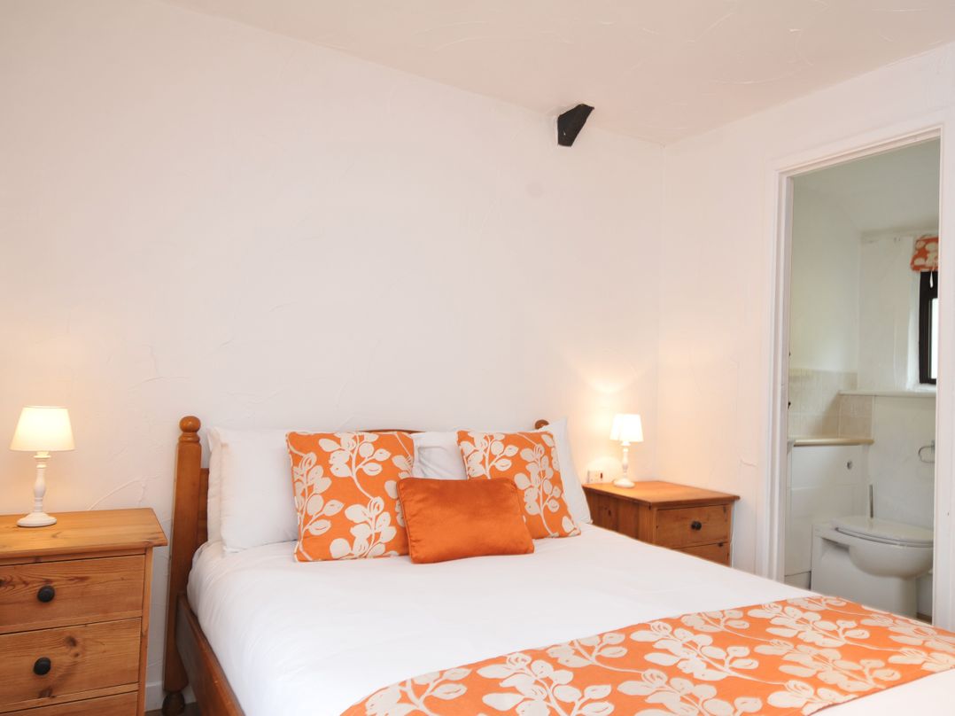 A bedroom with a bed and nightstand at Windbury Cottage in Hartland