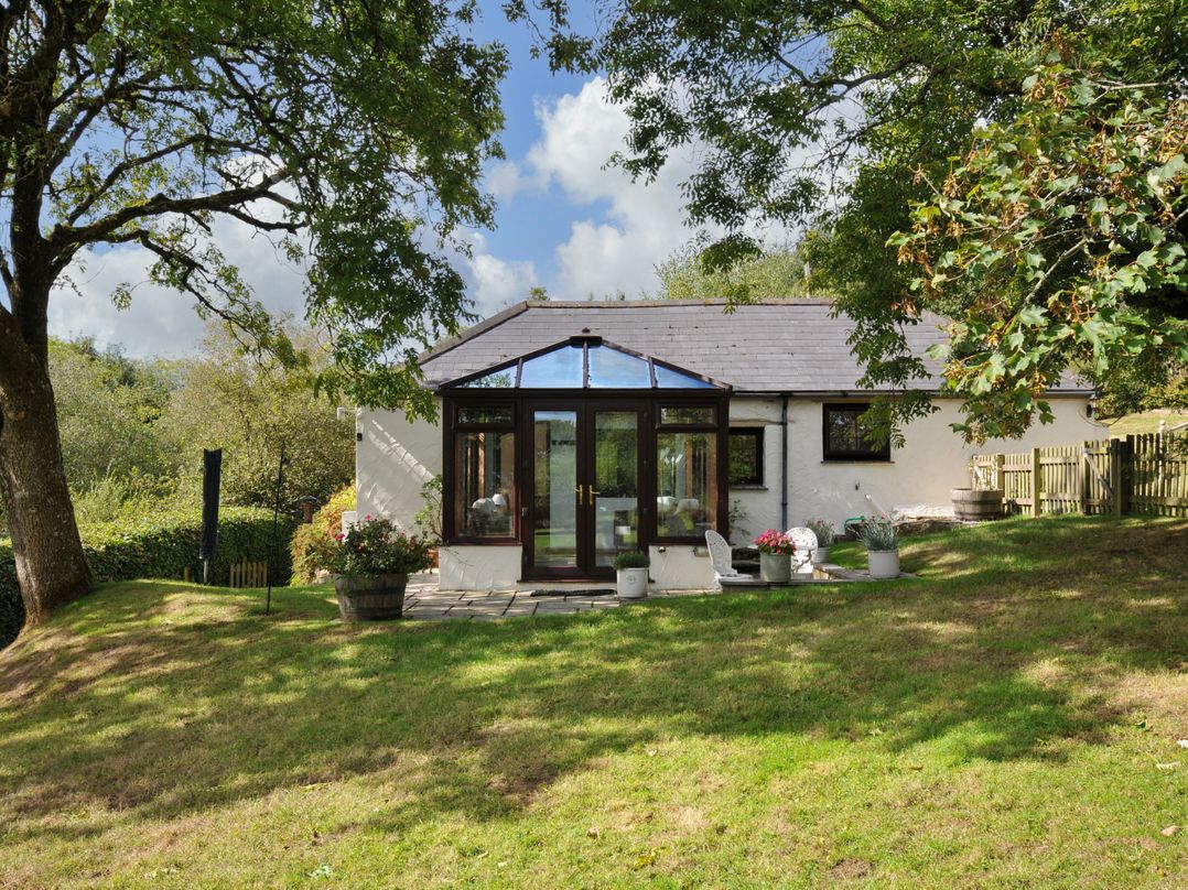 A backyard with a conservatory and planters at Barley Cottage in Hartland