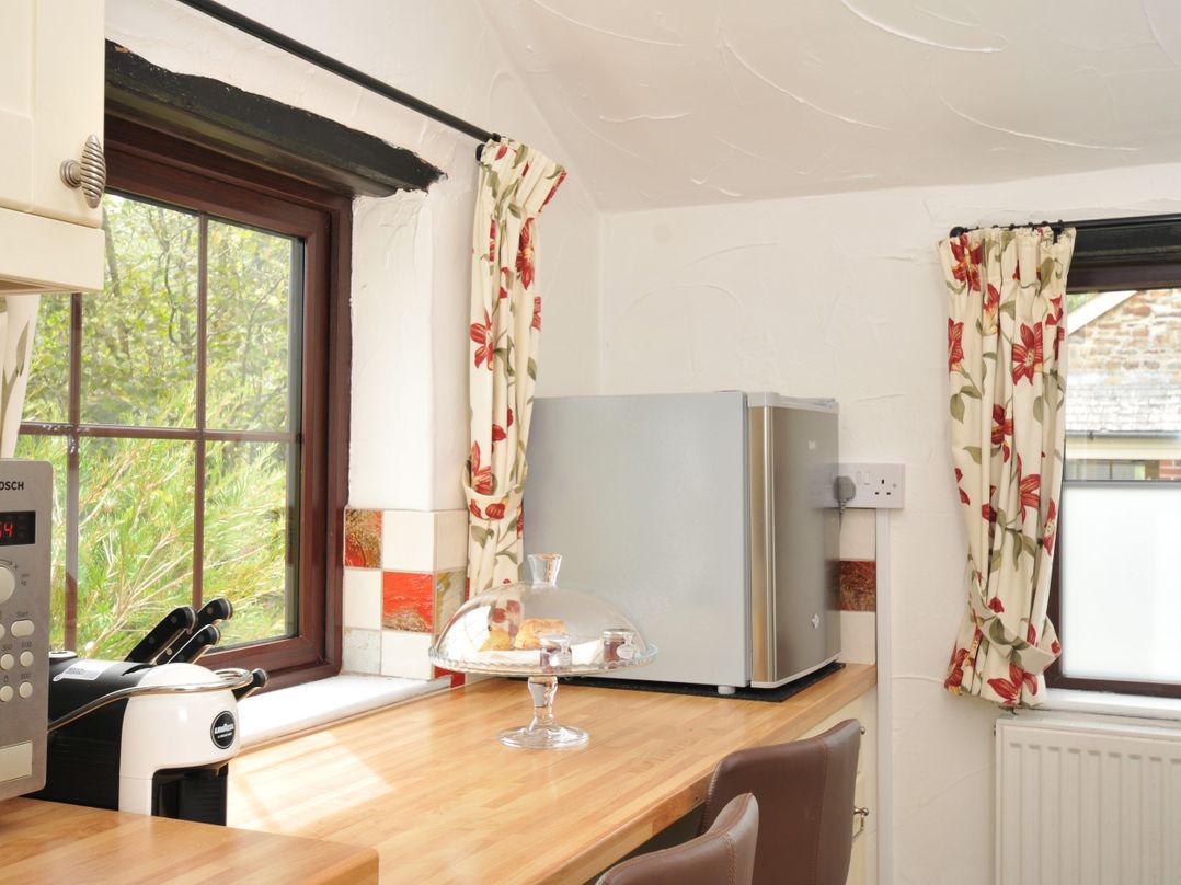 A kitchen with a microwave, refrigerator, and countertop at Barley Cottage in Hartland