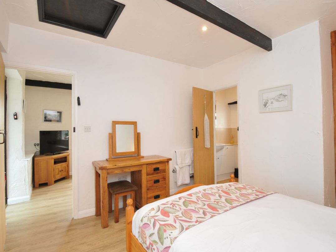A bedroom with a bed a dressing table and a tv at Barley Cottage in Hartland