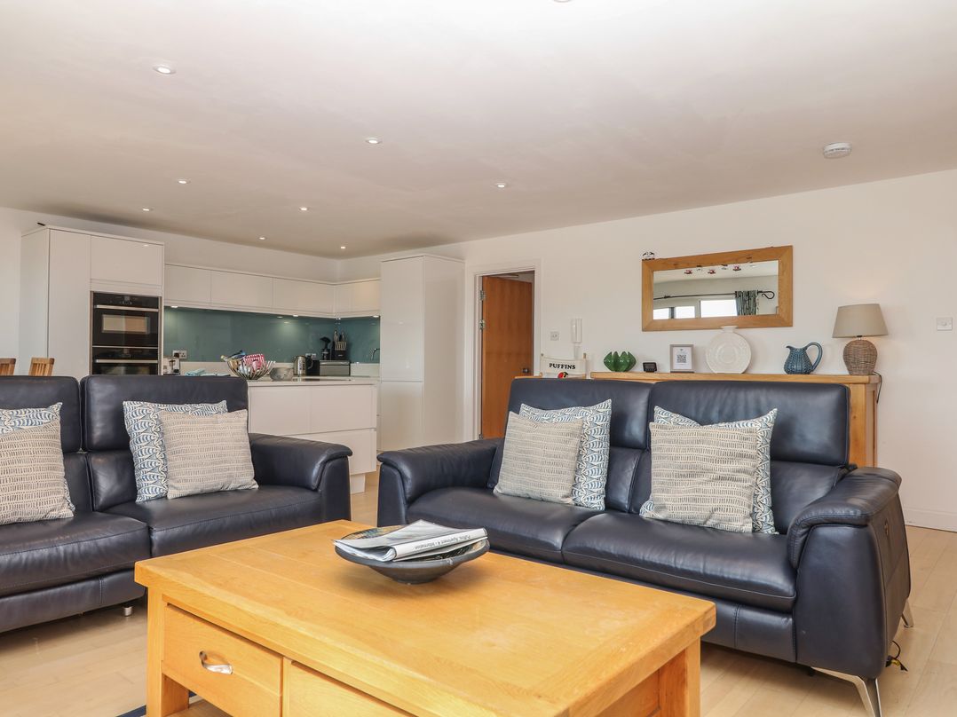 A living room with sofas and kitchen area at 4 Burgh Island Causeway in Bigbury