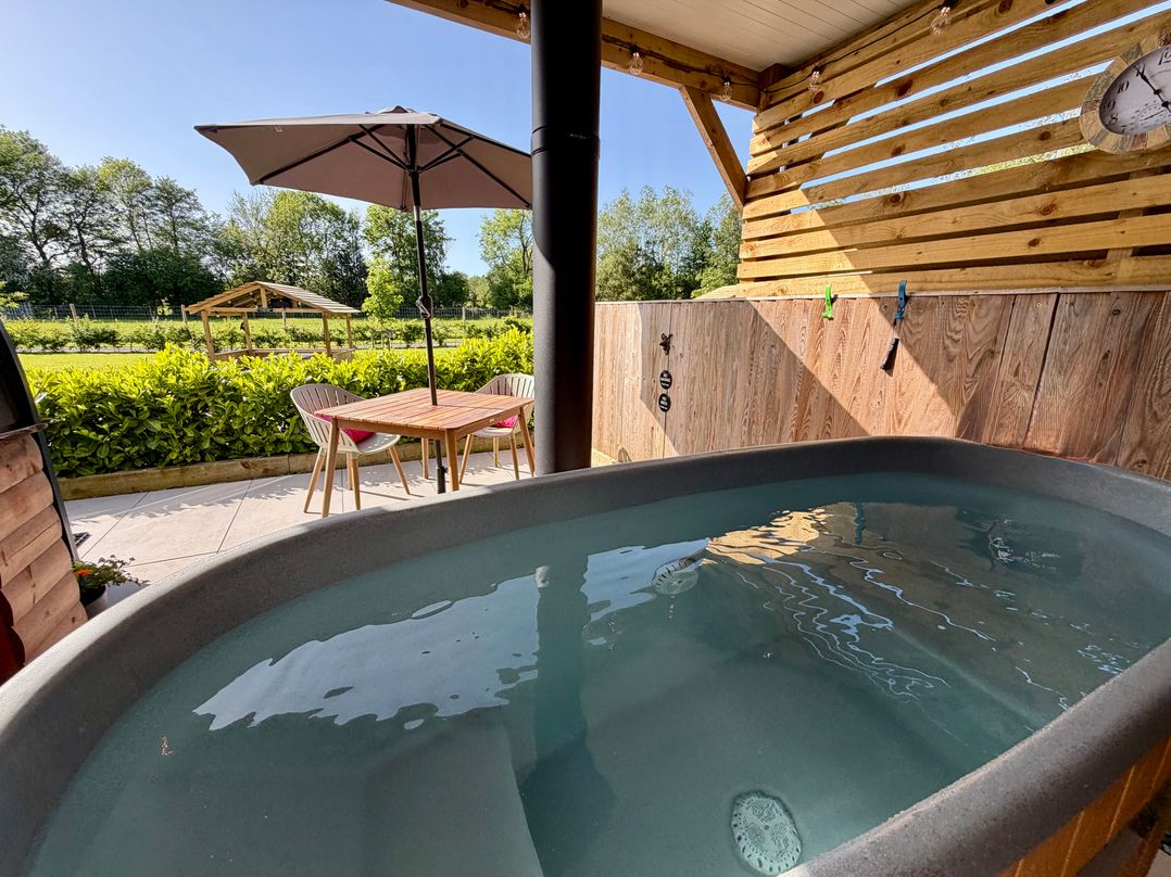 An outdoor area with a hot tub and table with chairs at Yes Deer in Ashbourne