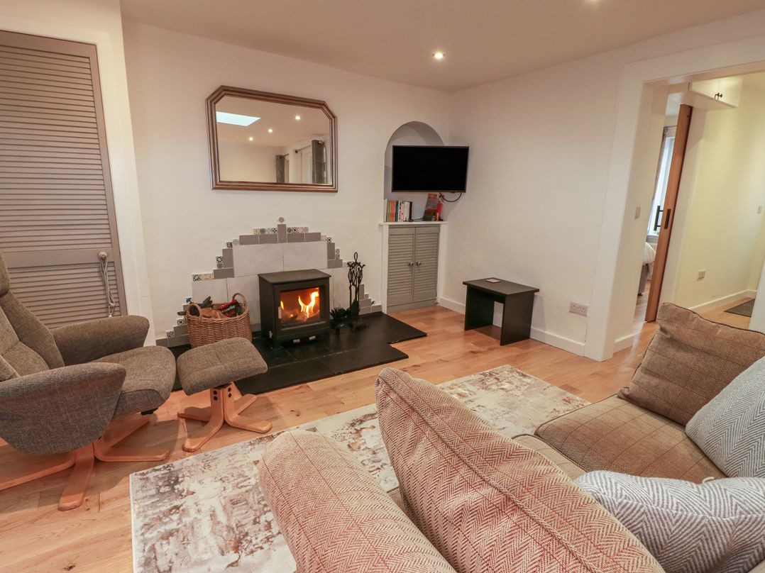 A living room with a fireplace and armchairs at Rosalin Cottage in Dreghorn near Irvine