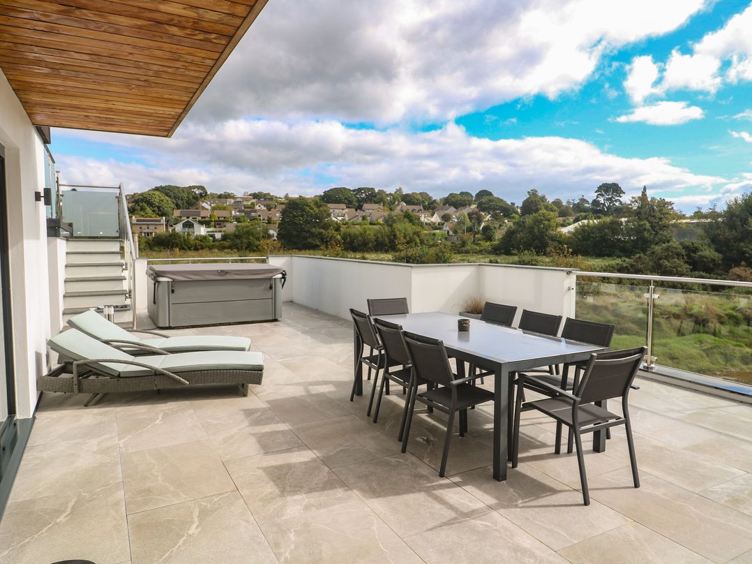 An outdoor terrace with seating and hot tub at Carnon Gwel, Devoran