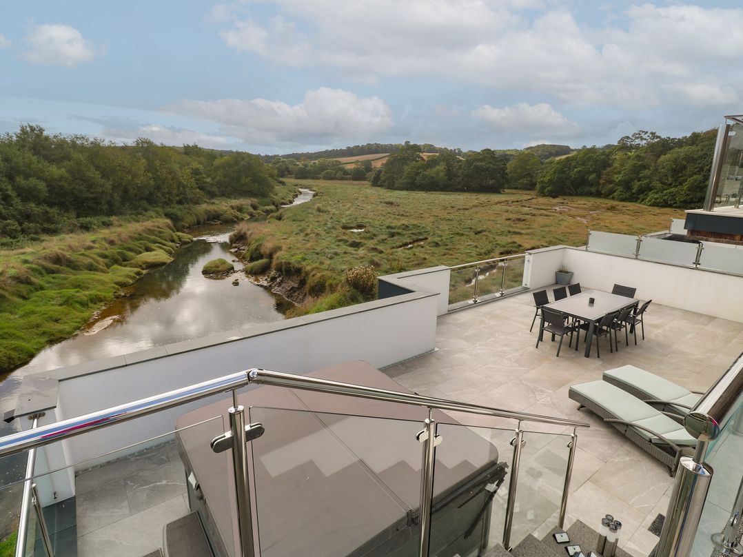 An outdoor area with a table and chairs overlooking a river at Carnon Gwel, Devoran