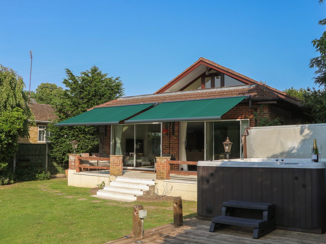 An outdoor area with a hot tub and a house at Coventina in Wraysbury