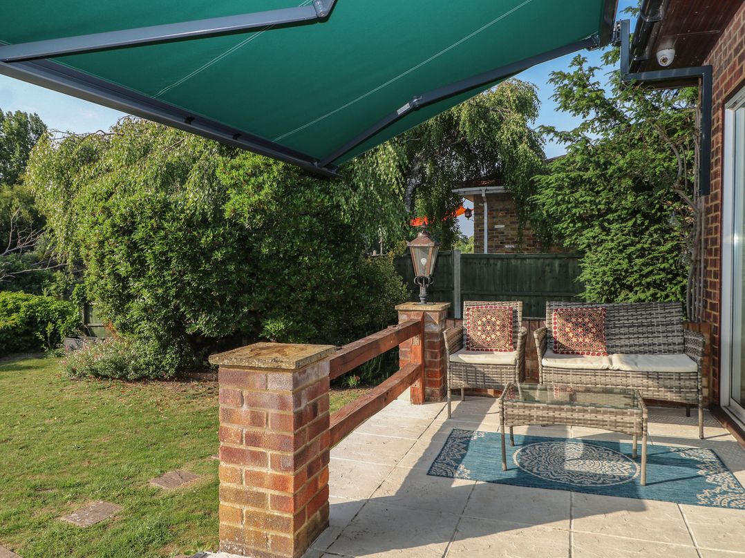 A garden with outdoor seating and a green awning at Coventina in Wraysbury