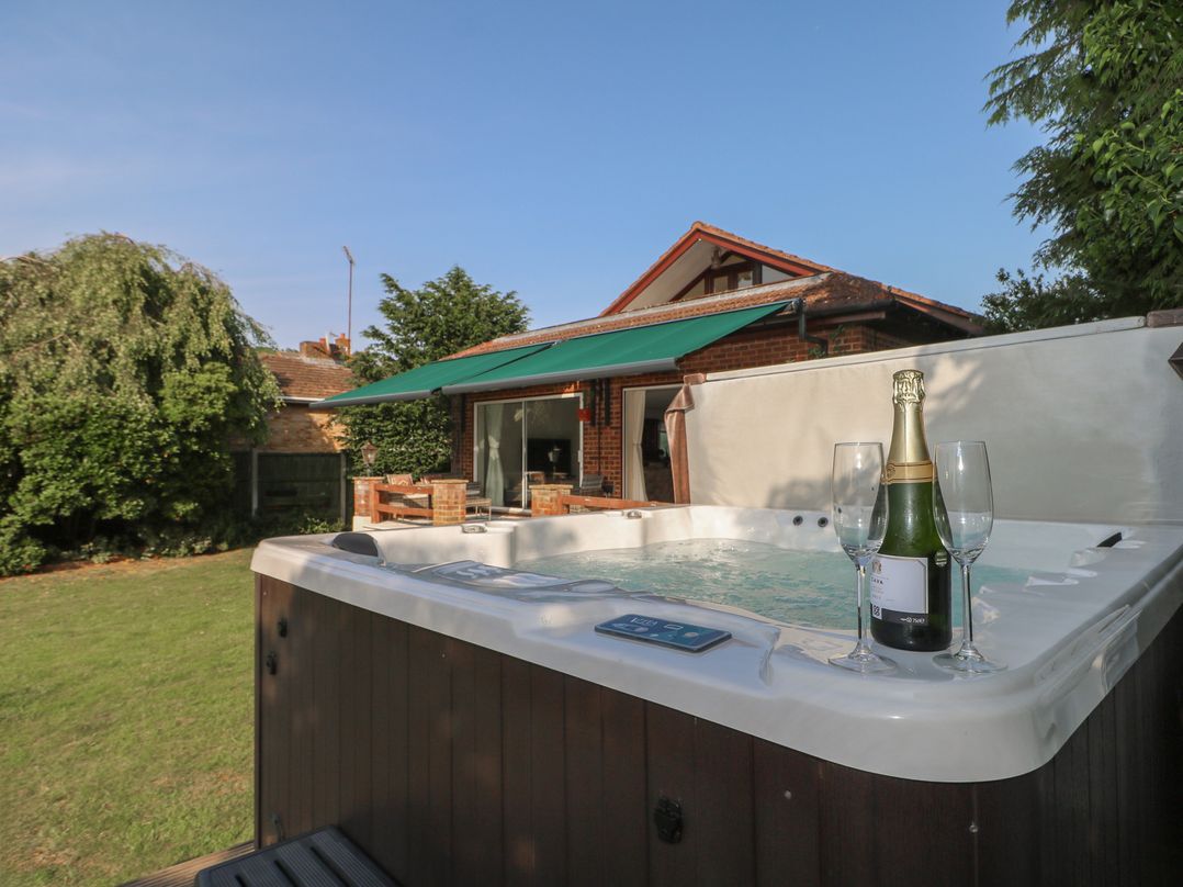 A hot tub with champagne and glasses in the garden at Coventina in Wraysbury