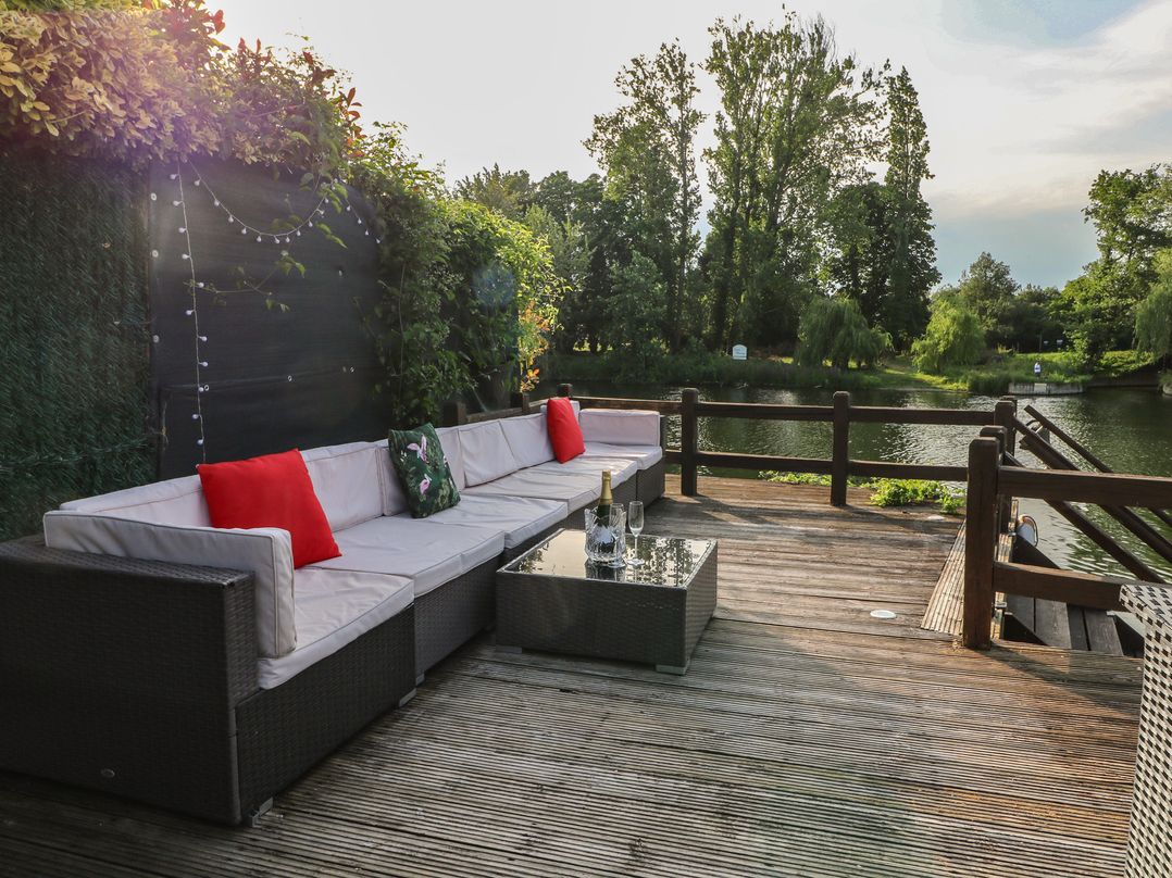 An outdoor seating area with a coffee table and view of the river at Coventina in Wraysbury
