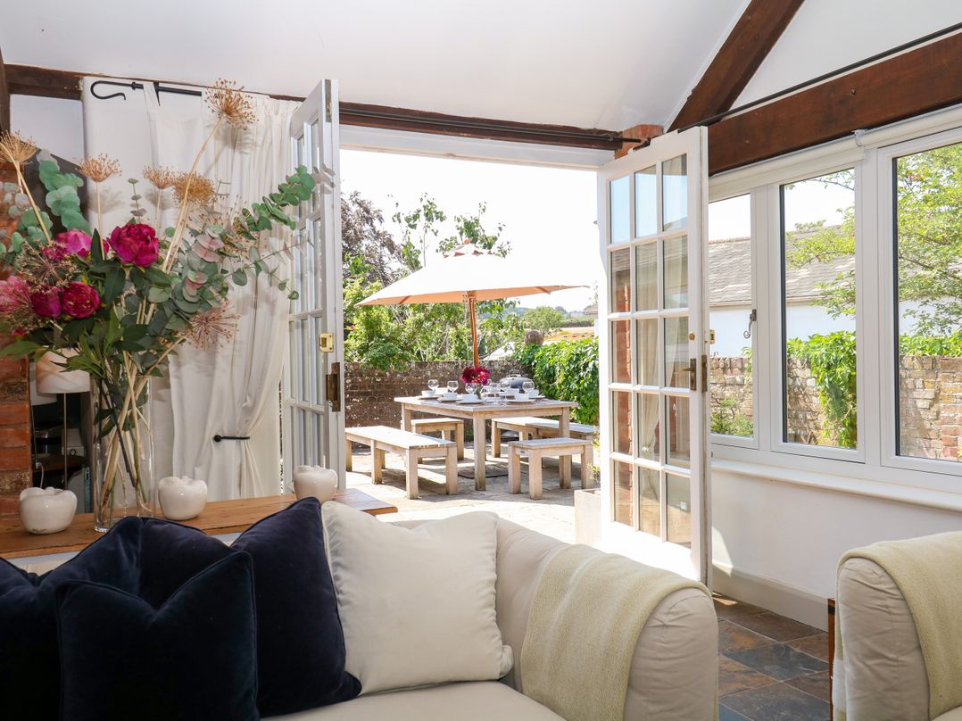A living room with a view to a dining area outside at Apple Mill in Venn Ottery near Sidmouth