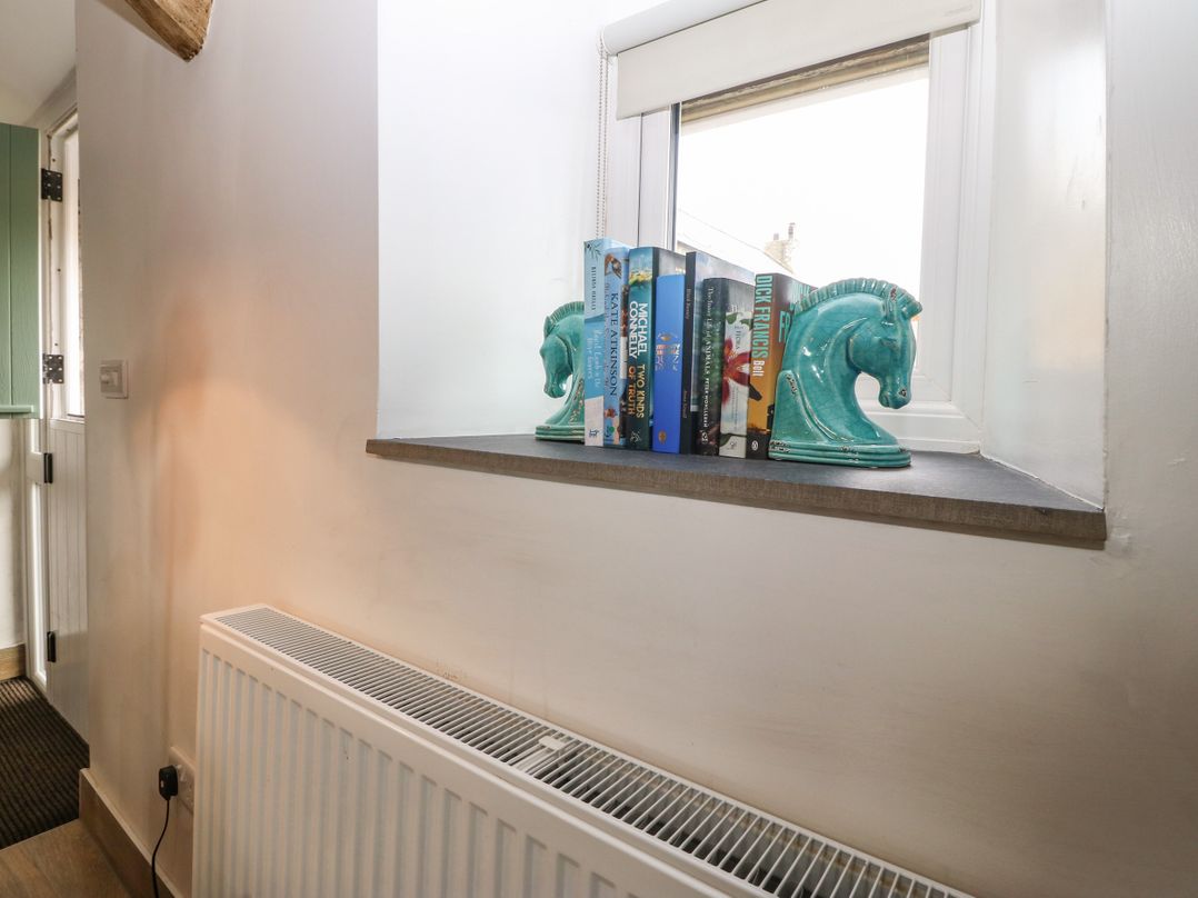 A windowsill with books held by horse head bookends above a radiator at Y Stabl in Dyffryn Ardudwy