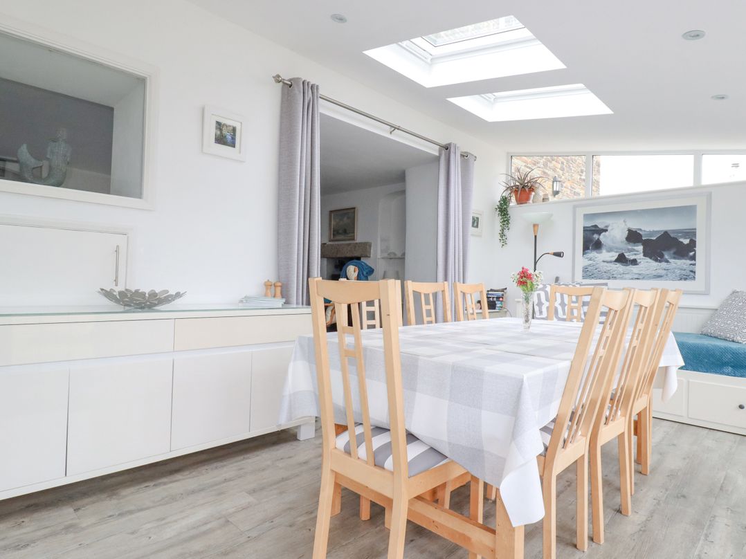 A dining room with wooden chairs and a table covered with a checkered tablecloth at Langurra in Crantock