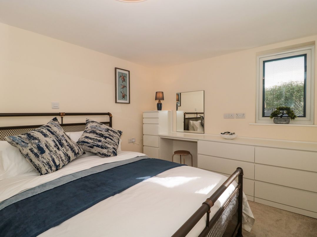 A bedroom with a bed and pillows a dresser with a mirror a lamp and a window at Minime in Weston-Super-Mare